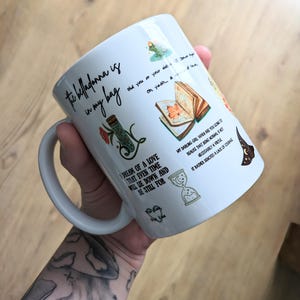 Puede incluir: Una taza de cer&aacute;mica blanca con varias ilustraciones coloridas y texto en negro. El texto dice: The belladonna is in my bag, did you or your sister, oh yeah, a matter of time, I dream of a love that even time will lie down and be still for.
