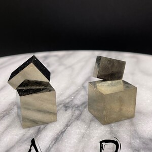 May include: Two stacks of pyrite crystals, labeled A and B. The crystals are a metallic gold color and have a cubic shape.