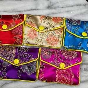 May include: Six small, colourful pouches with floral patterns and yellow trim. Each pouch has a yellow button closure.