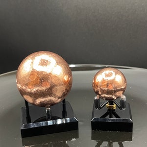 May include: Two copper spheres on black stands. The larger sphere is about 3 inches in diameter and the smaller sphere is about 1.5 inches in diameter.