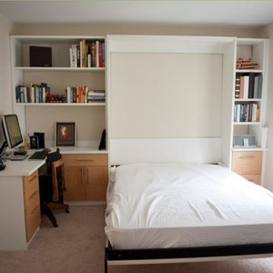 May include: A white wall bed with a white mattress and a white headboard. The bed is in a room with a desk, a chair, and bookshelves on either side of the bed.
