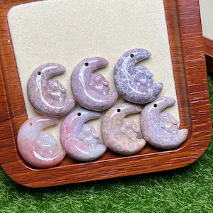 May include: Seven crescent moon shaped pendants made of fossilized coral. The pendants are in various shades of pink, white, and gray. Some of the pendants have a floral pattern, while others have a more abstract design.