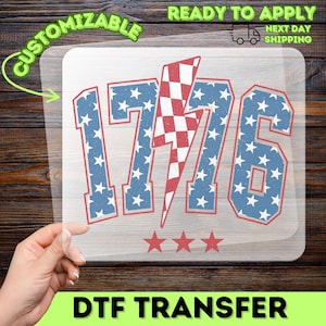 May include: A DTF transfer with the number "1776" in blue with white stars and red trim. A red and white chequered lightning bolt is in the centre. Three red stars are below the numbers. The words "CUSTOMIZABLE" and "READY TO APPLY" are in the image.