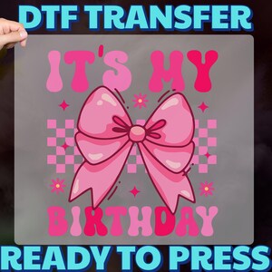 May include: A pink DTF transfer featuring the text "IT'S MY BIRTHDAY" and a large pink bow. The design includes pink stars, flowers, and a checkered pattern. The words "READY TO PRESS" are at the bottom.
