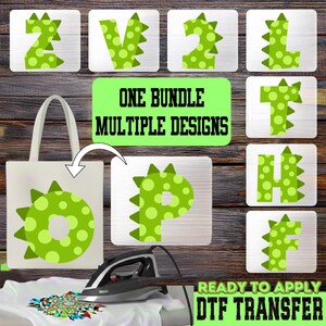 May include: A collection of green dinosaur-themed designs, including letters and a tote bag graphic. The designs feature a light green color with darker green polka dots and spikes. The text "ONE BUNDLE MULTIPLE DESIGNS" and "READY TO APPLY DTF TRANSFER" are also visible.