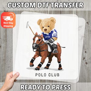May include: A DTF transfer featuring a teddy bear in a polo uniform riding a brown horse. The bear wears a blue and white jersey with the number 03 and the word "CAPTAIN". The words "POLO CLUB" and "READY TO PRESS" are also visible.