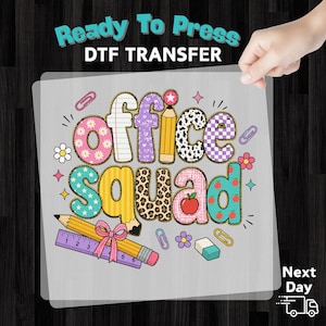 May include: A Ready To Press DTF TRANSFER sheet featuring the text office squad in colorful, patterned letters. The design includes illustrations of pencils, a purple ruler, a pink bow, paper clips, a small eraser, and flowers.