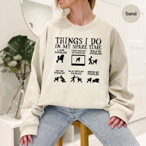 a woman sitting on a stool wearing a sweatshirt that says things i do in my