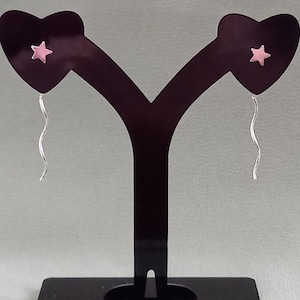 May include: A pair of silver heart-shaped earrings with pink star charms and dangling silver chains.