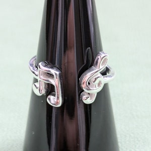May include: A silver ring featuring a treble clef and a musical note design.