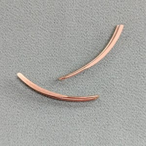 May include: Two rose gold hair clips in a curved shape.