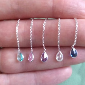 May include: Five silver chains with teardrop-shaped gemstones. The gemstones are blue, pink, purple, clear, and light blue.