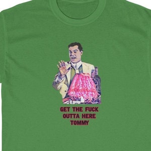 Puede incluir: Camiseta verde con una ilustración retro de un hombre gesticulando. La imagen incluye un objeto rosa y botellas, con el texto "GET THE FUCK OUTTA HERE TOMMY" en rojo y blanco.