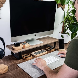 A man working at a desk with a monitor stand