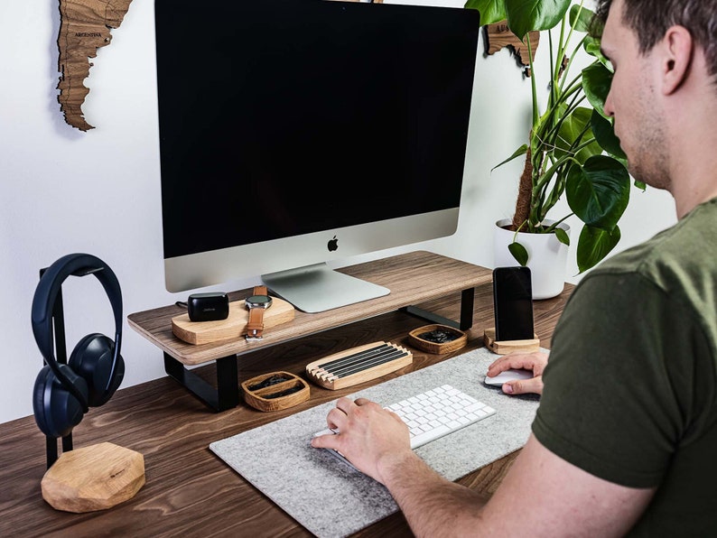 A man working at a desk with a monitor stand