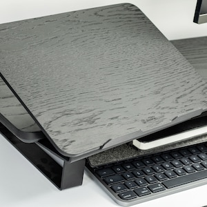 May include: A black wooden laptop stand with a tilting top. The stand is adjustable and can be raised or lowered to different heights. The stand is made of a durable material and is designed to support the weight of a laptop.