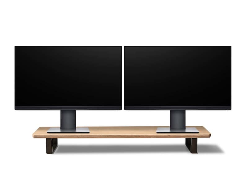 Pu&ograve; includere: Due monitor per computer neri con cornici sottili sono montati su un supporto in legno con gambe in metallo nero. Il supporto &egrave; su una superficie bianca.