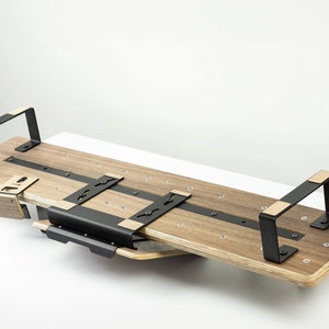 May include: A wooden and black metal shelf unit with two brackets. The shelf is made of light brown wood and has a black metal frame. The shelf is mounted to the wall with two black metal brackets.