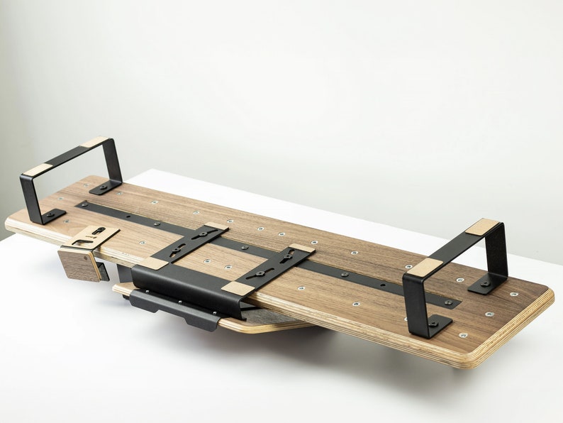 May include: A wooden and black metal shelf unit with two brackets. The shelf is made of light brown wood and has a black metal frame. The shelf is mounted to the wall with two black metal brackets.