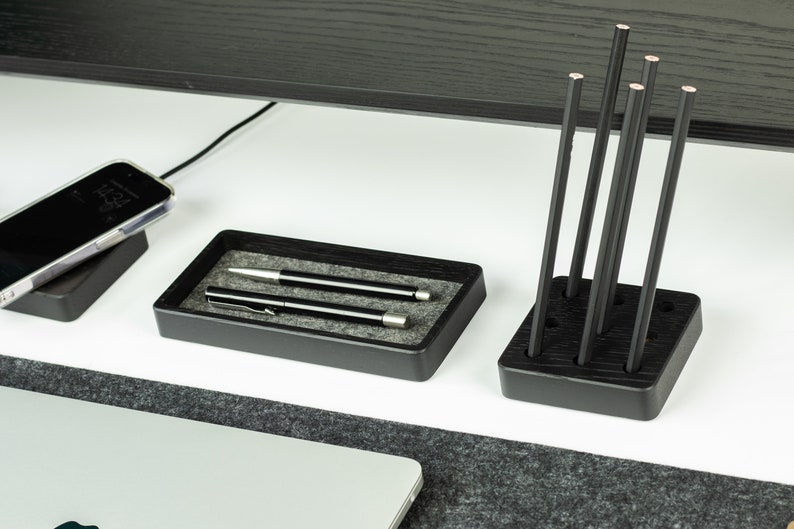 May include: Black wooden desk organiser with two compartments. One compartment holds two silver pens and the other holds six black pencils.
