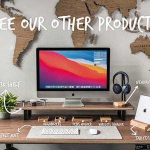 May include: A wooden desk shelf with a computer monitor, a plant, a drone, and various desk accessories, including organisers, a pen holder, a wireless charger, a headphone stand, and a tablet/laptop stand. The text "SEE OUR OTHER PRODUCTS" is written above the desk shelf. The text "DESK SHELF", "HEADPHONE STAND", "ORGANISERS", "PENS HOLDER", "WIRELESS CHARGER", "FELT MAT", and "TABLET/LAPTOP STAND" are written on the image.