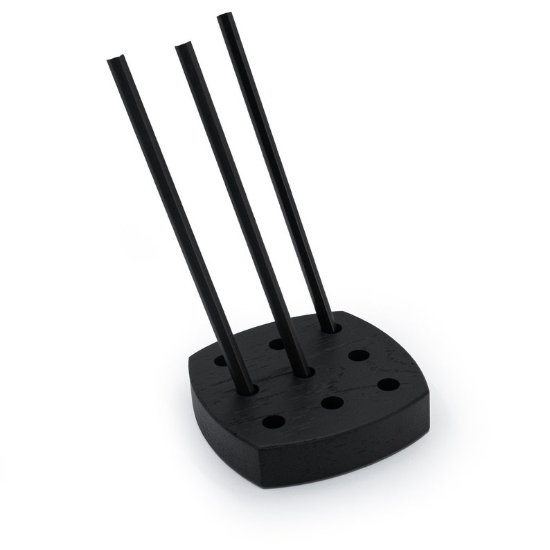 May include: Black wooden stand with six holes for holding drinking straws. Three black straws are inserted into the stand.