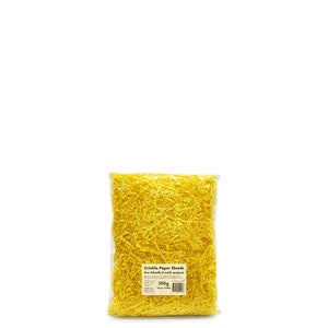 Op de afbeelding: Een doorzichtige plastic zak gevuld met felgele gerimpelde papieren stroken. De zak heeft een label met de tekst "Crinkle Paper Shreds Eco friendly & multi purpose 100g Sunny Yellow".