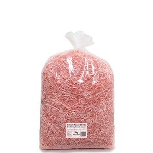 Op de afbeelding: Een grote plastic zak gevuld met licht perzikkleurige gekreukelde papieren stroken. De zak heeft een label met de tekst "Crinkle Paper Shreds Eco-friendly & multi-purpose 1kg Light Peach".