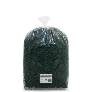 Op de afbeelding: Een grote plastic zak gevuld met 1 kg groene kreukelpapierstroken. De zak heeft een label met de tekst "Crinkle Paper Shreds Eco friendly & multi purpose 1kg Hunter Green".