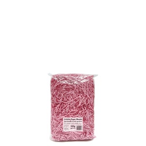 Op de afbeelding: Een doorzichtige plastic zak gevuld met lichtroze crinkle papiersnippers. De zak heeft een label met de tekst "Crinkle Paper Shreds" en "100g Light Pink". De snippers zijn milieuvriendelijk en multifunctioneel.