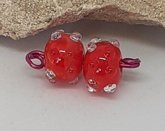 Deux perles de verre filées à la flamme, rouge et transparent