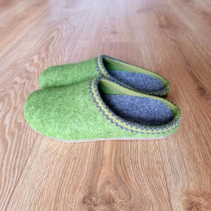 Puede incluir: Un par de zapatillas de fieltro verde con interiores grises y ribetes decorativos. Las zapatillas est&aacute;n hechas de un material suave y texturizado y est&aacute;n dise&ntilde;adas para uso en interiores. Miden unos 25 cm de largo.