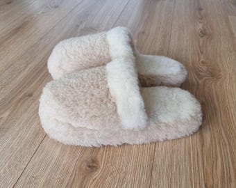 Könnte beinhalten: Ein Paar flauschige Hausschuhe in Beige und Weiß. Die Hausschuhe sind aus weichem, plüschigen Material gefertigt und haben ein schlichtes, bequemes Design.
