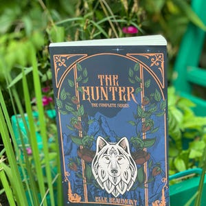 Peut inclure: Une couverture de livre avec un fond bleu foncé et une illustration de loup blanc. Le titre du livre est "The Hunter: The Complete Series" et l'auteur est "Elle Beaumont".