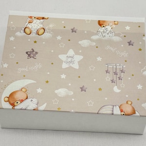 May include: A rectangular box with a light beige lid featuring a repeating pattern of sleeping teddy bears, clouds, stars, and the words "good night." The box has a white base and is likely for baby items.