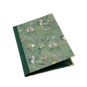 May include: A green binder featuring a botanical print of various flowers and herbs on the cover. The spine is a solid dark green, and the corners are reinforced with gold-toned metal accents. The interior mechanism is visible at the bottom.