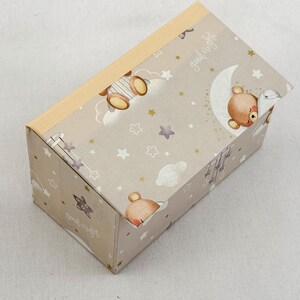 May include: A rectangular gift box with a light beige background, adorned with a repeating pattern of teddy bears, stars, and clouds. The box features the words "good night" in a script font. The lid is a light tan color.