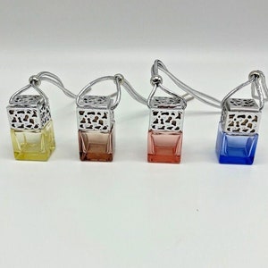 May include: Four car air fresheners with decorative metal cages and hanging cords. The air fresheners are filled with coloured liquid and come in yellow, pink, red, and blue.