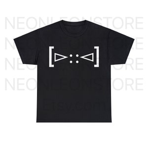 Puede incluir: Camiseta negra con un diseño gráfico blanco. El diseño presenta dos triángulos enfrentados, con dos puntos en el medio, todo encerrado entre corchetes. La camiseta es de cuello redondo.
