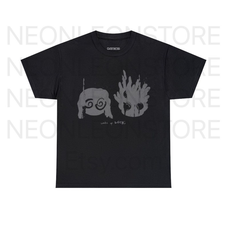 May include: Black t-shirt featuring two gray graphic illustrations and the text "wake up LOCKI." The illustrations include a face with spiral eyes and a flame-like design. The shirt has a crew neck and short sleeves.