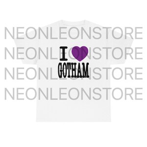 Peut inclure: T-shirt blanc avec un c&oelig;ur violet et le texte "I love Gotham" en noir.