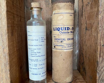 May include: Two vintage glass bottles, one with a cork stopper and the other with a metal lid. Both bottles have labels with text that reads "LIQUID F Outside Mail" and "CHEMICAL ENGINEER DALLAS".