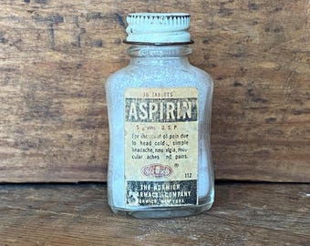 May include: A vintage glass bottle of aspirin tablets with a white label that reads "36 Tablets Aspirin 5 grains U.S.P. For the relief of pain due to head cold, simple headache, neuralgia, muscular aches and pains. The Norwich Pharmacal Company Norwich, New York 112"