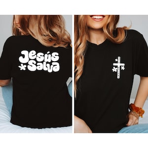 May include: Black t-shirts with white text and graphics. One shirt has "Jesús Salva" with flower accents on the back. The other shirt has a cross graphic with "Gracias Dios" and flower accents on the front.