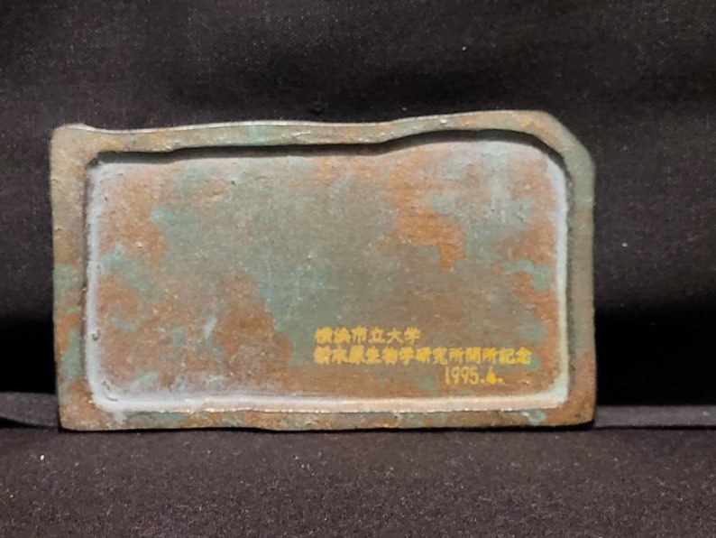 Op de afbeelding: Een rechthoekige bronzen plaquette met een groene patina. De plaquette heeft een gouden opschrift met de tekst "National Taiwan University, Institute of History, Department of History, 1995.6."