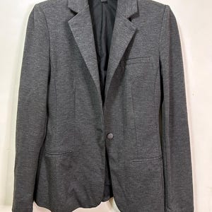 May include: A charcoal gray blazer with a single-button closure. The blazer has a notched lapel, two front pockets, and a black lining. The jacket is hanging on a white hanger against a white background.