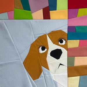 Pode incluir: Uma colcha de retalhos com o rosto de um cão com detalhes em castanho, branco e preto. A cabeça do cão está sobre um fundo azul claro, com um padrão geométrico colorido na parte superior e direita. A colcha é feita de tecido.