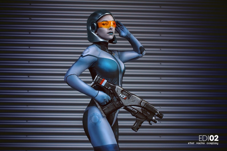 May include: A person in a futuristic blue and black bodysuit with a helmet and orange visor, holding a large gun. The image has the text "EDI02" and "star nacho cosplay".
