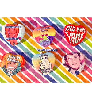 Peut inclure: Six broches en forme de cœur avec différents motifs et dictons. Les broches présentent un fond arc-en-ciel avec des paillettes. Les dictons sur les broches incluent "everyone is so mean 2 me", "It's been one of those weeks... Pass the Yaci!!!", "Old Man Yaci", "I See No Difference Love Is Love", "Let's Take Ibuprofen Together", et une broche avec un portrait d'un homme.