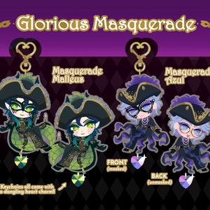 May include: Two colorful keychains featuring cartoon characters from the anime "Twisted Wonderland". The characters are dressed in masquerade costumes and have a heart charm attached to the keychain. The text "Masquerade Malleus" and "Masquerade Azul" are visible on the keychains.